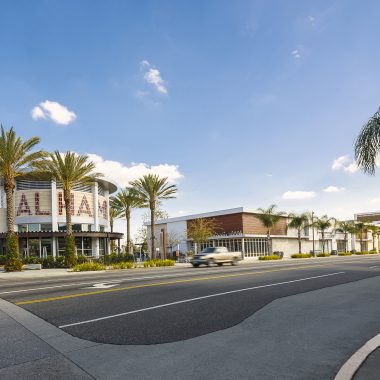 Shopping center with palm trees and road.