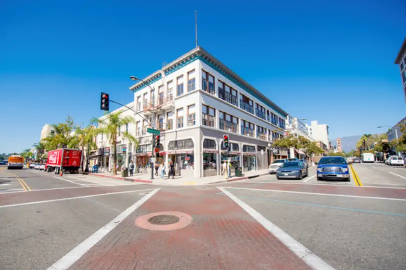 Street intersection with historic building and cars.