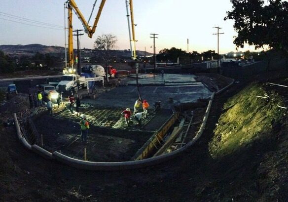 Construction site with workers and machinery at dusk.