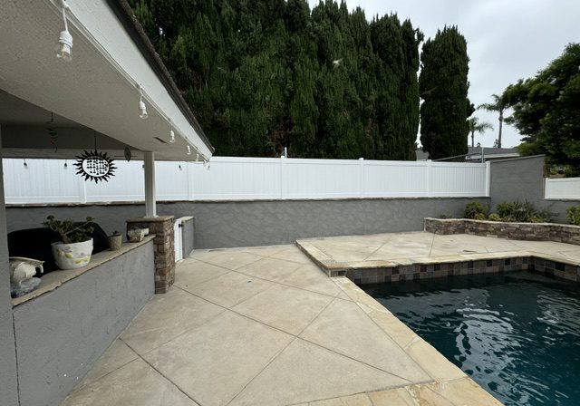 Backyard patio with pool and trees.