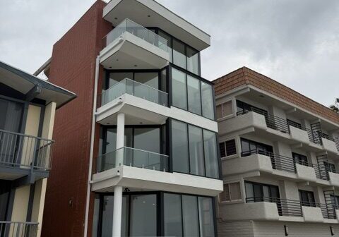 Modern beachfront apartment building under cloudy sky.